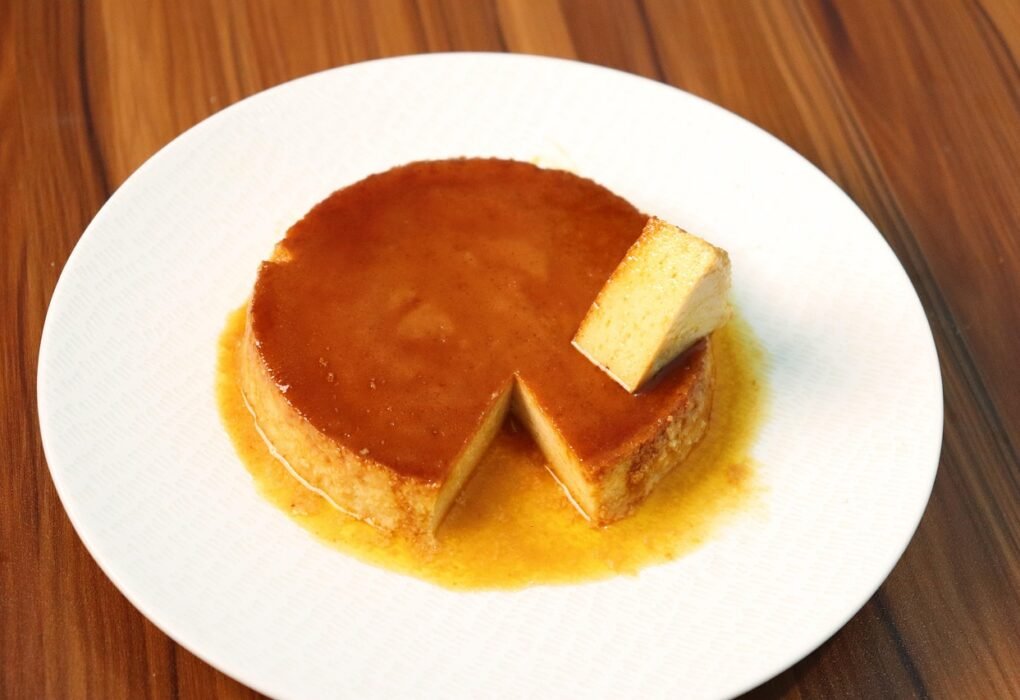Flan casero con caramelo y una porción cortada en un plato blanco