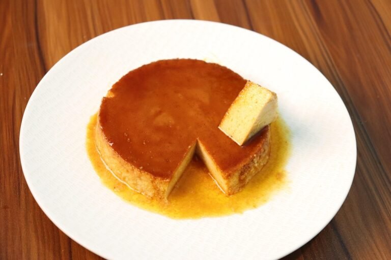 Flan casero con caramelo y una porción cortada en un plato blanco