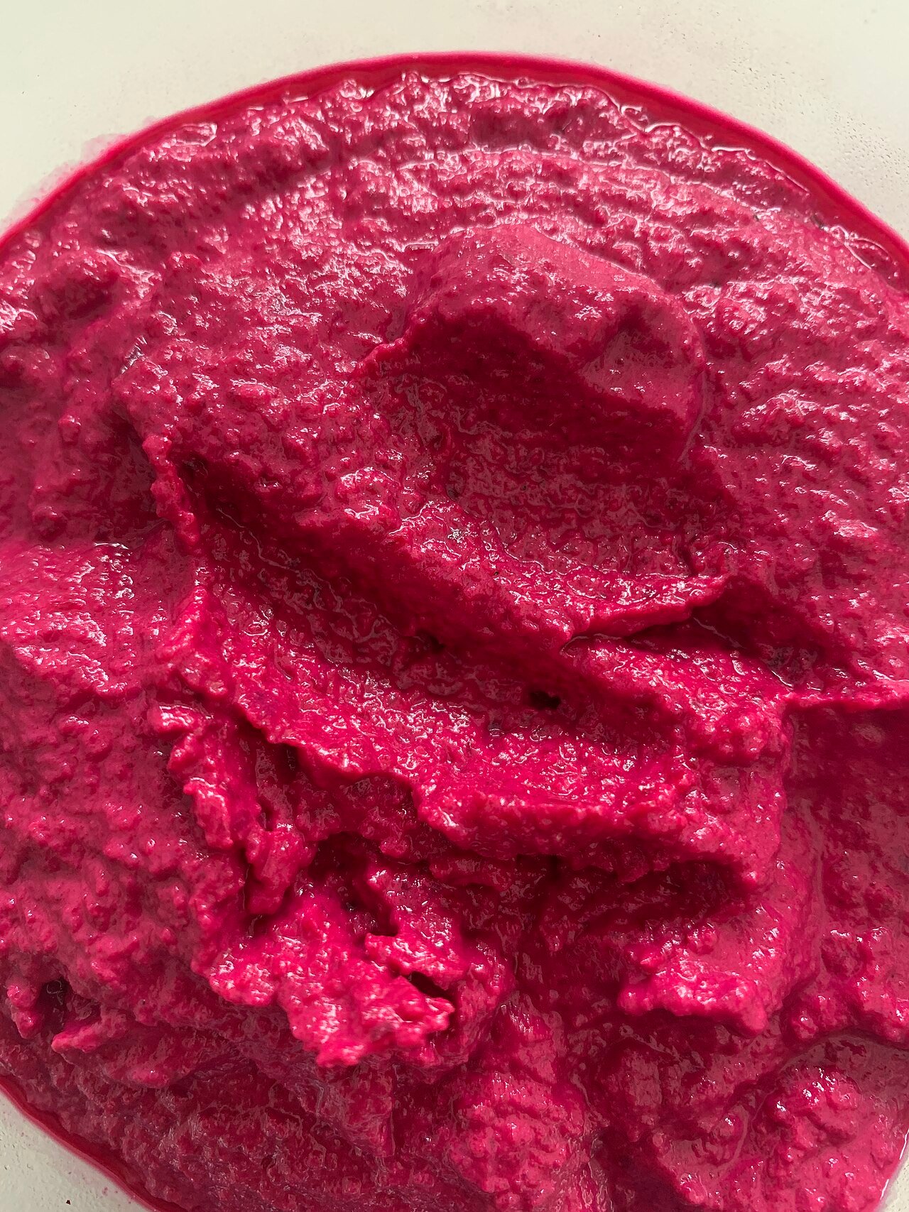 Hummus de remolacha de color rosa intenso en un bol.