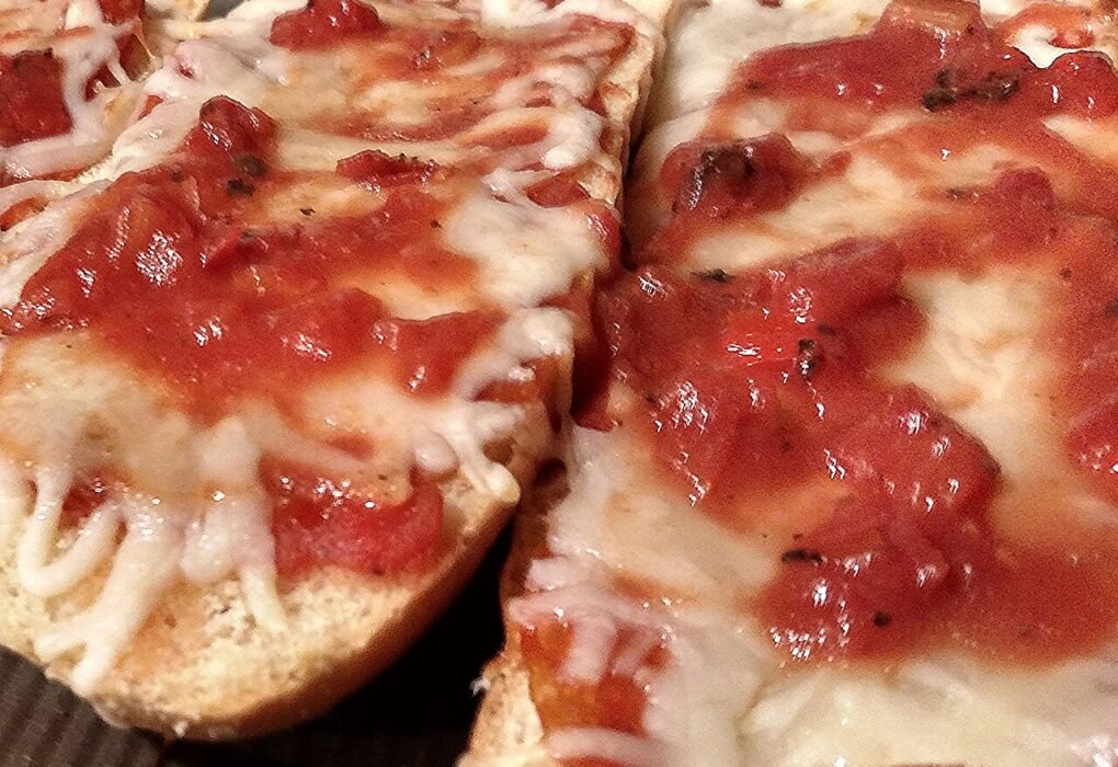 Rebanadas de pan con tomate y queso fundido en una bandeja de horno.