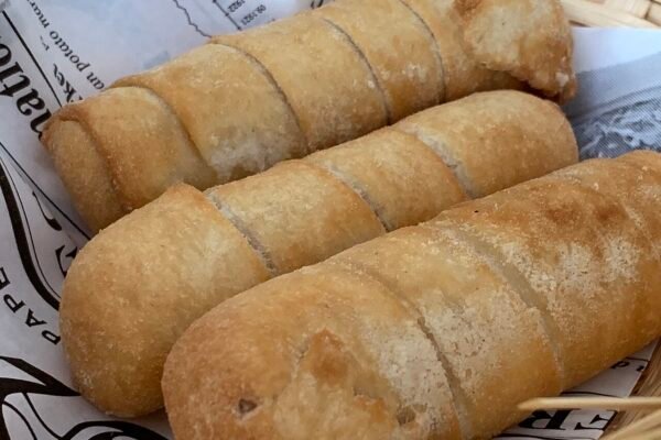 Tres tequeños fritos dorados en un recipiente con papel de estraza.